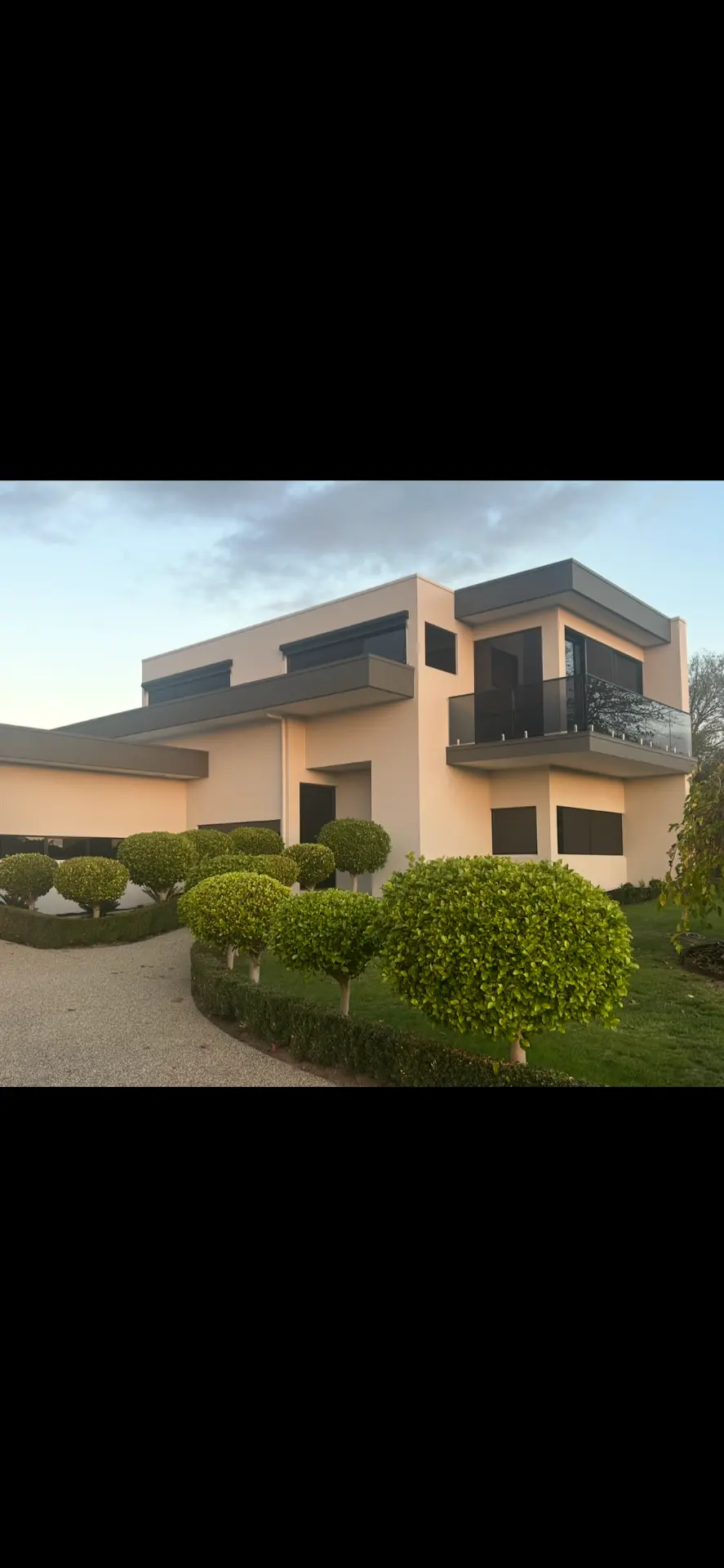 Two storey rendered home with warm cream render finish at dusk