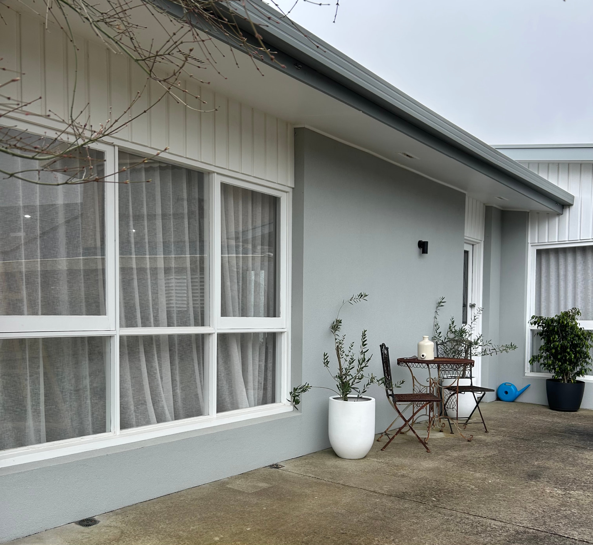 Rendered home exterior in soft grey with white weatherboard gable